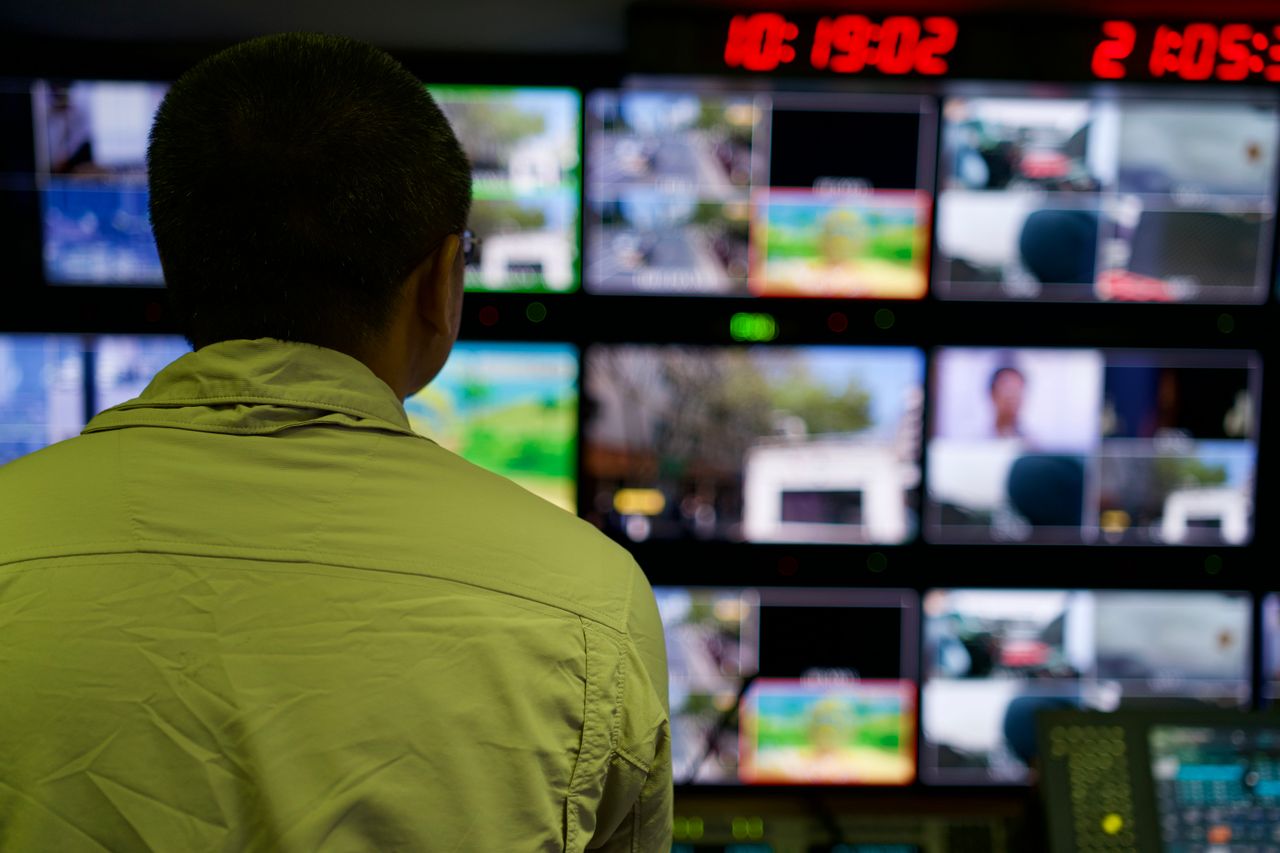 services-03 Man in a control room overseeing multiple monitors displaying various scenes.