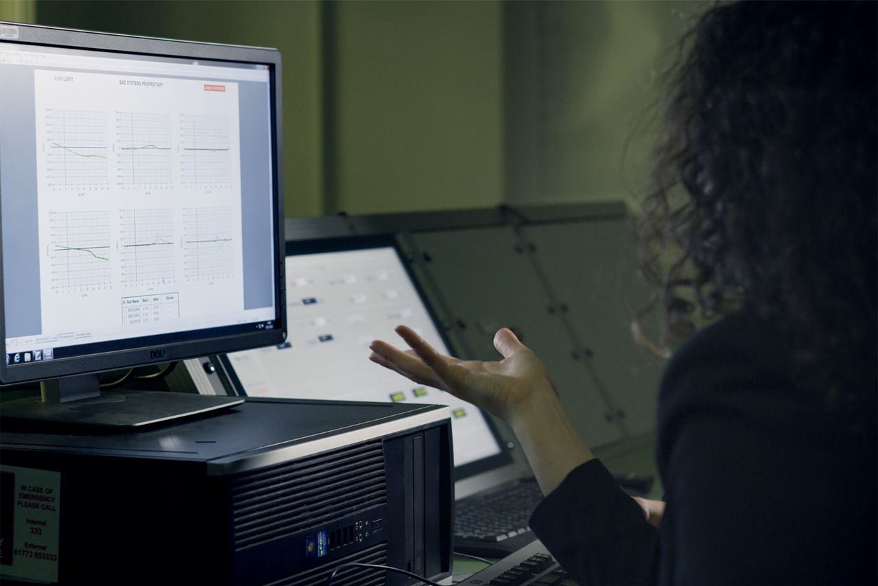 ours-journey A woman analyzes data on a computer screen in a modern office setup, focusing on technological research.